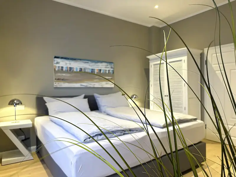 Ferienwohnung Inselrose Juist – Wohnzimmer mit Sofa, Couchtisch und Terrasse
